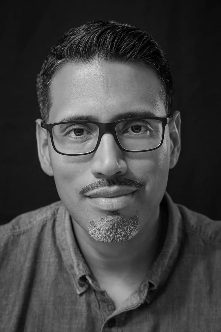 Black and white image of Nery Lemus, a man with glasses looking directly at the camera with a subtle smile