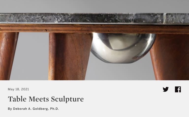 Above: close detail of a side view of a table by Isamu Noguchi, showing the profile of its wooden base and legs, marble top, and embedded metal bowl; below: the article title Table Meets Sculpture and the author name Deborah A. Goldberg