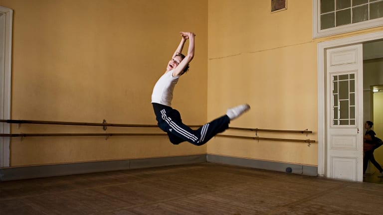 Photograph of a child leaping into the air in a ballet classroom.