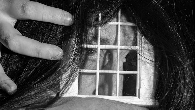 person with black hair holding a small window up to their eye.