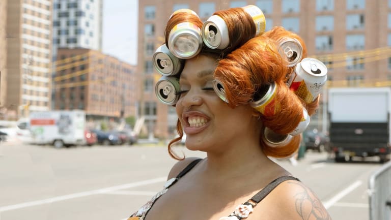 Portrait of woman with red hair wearing soda cans as hair rollers