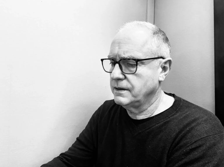 black and white image of an old man in black glasses and a black t shirt 