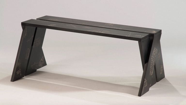 Minimalist wood bench, dyed black with illustrations carved into surface