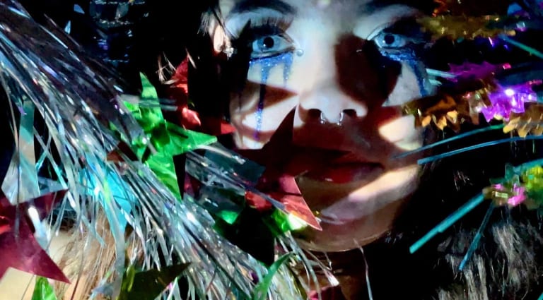 Photographic image of a woman's face with glitter tear makeup running down her eyes.