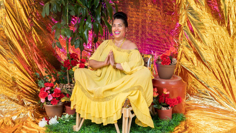 A portrait of a person in a yellow dress among potted plants. 