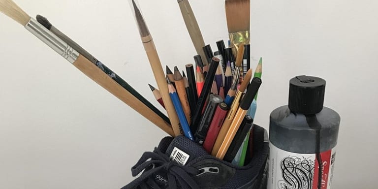 A shoe, filled with drawing implements, and a bottle of black ink