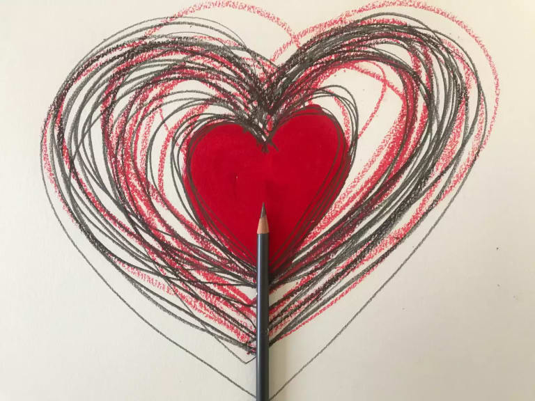 Valentine's heart drawn in graphite and red pencil with a smaller painted red heart at the center and a pencil laid on top painting upward