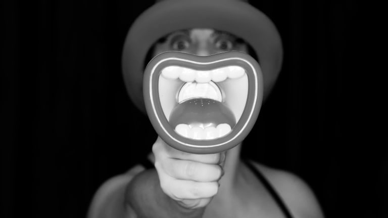 a women face covering by a megaphone. Black & white photo. Black background