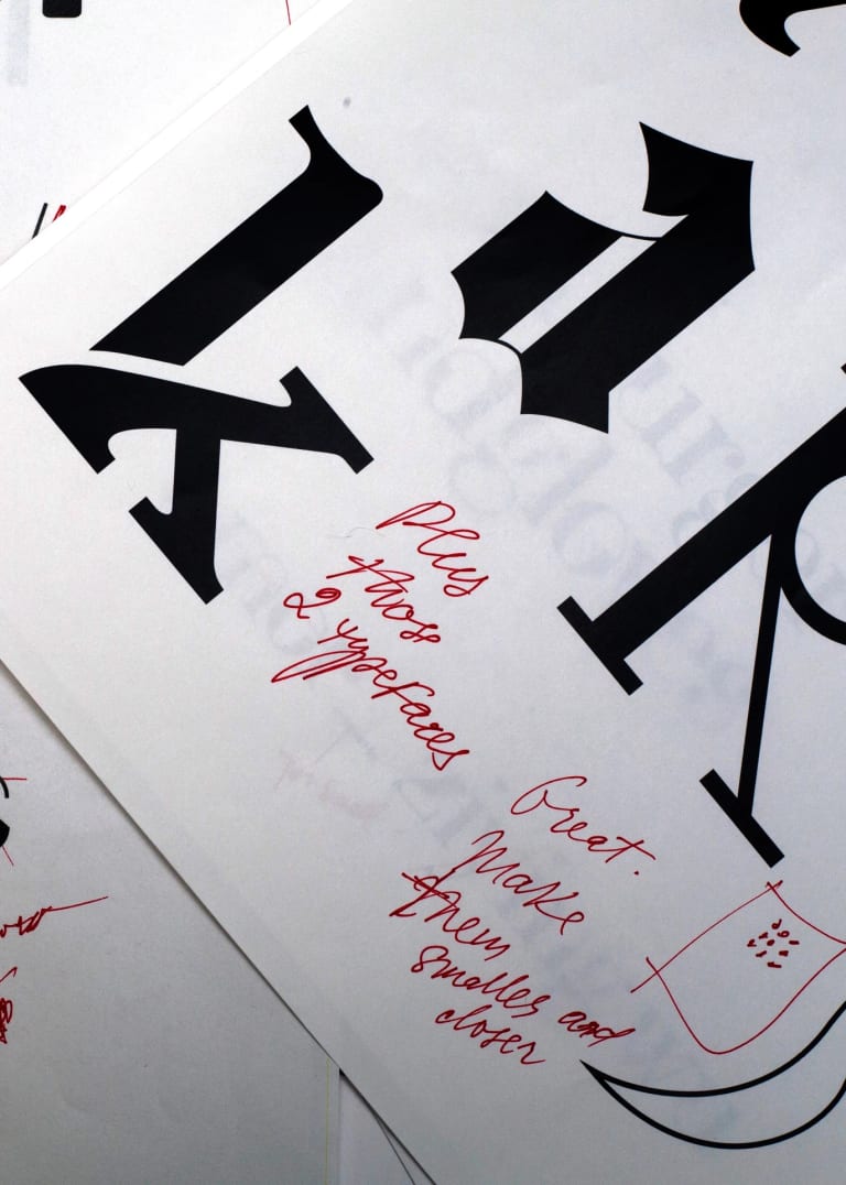 A design for a new font done on paper, scribbled up with feedback in red ink.