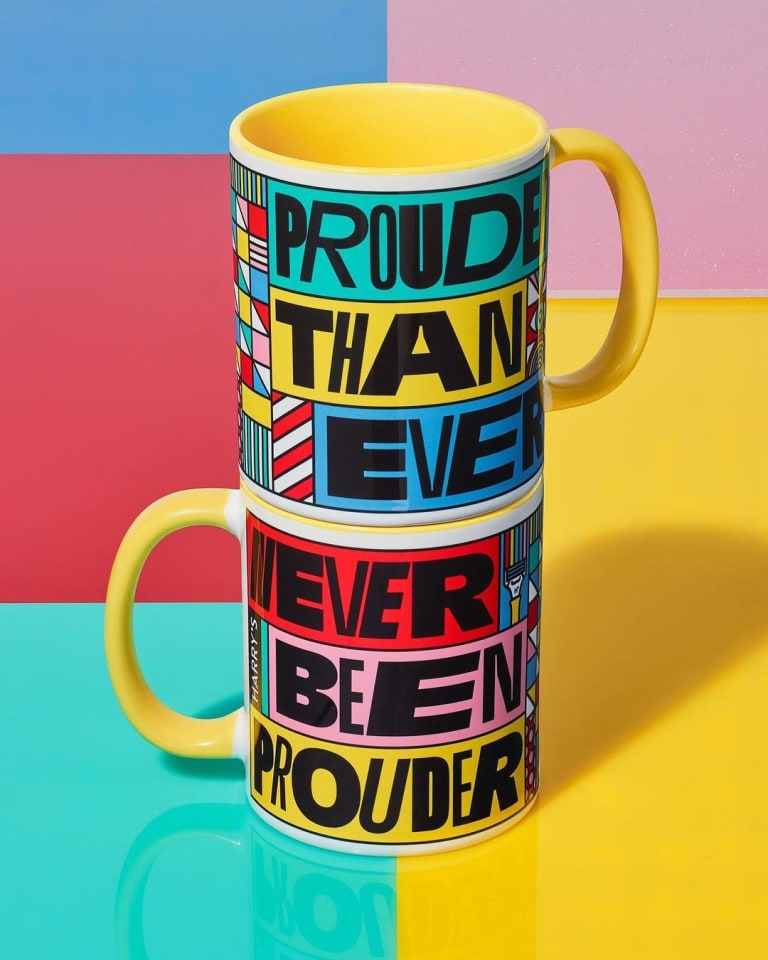 Two stacked coffee mugs. One says "Prouder than ever" and one says "Never been prouder." They both feature blocks of color, signifying gay pride for Pride Month.