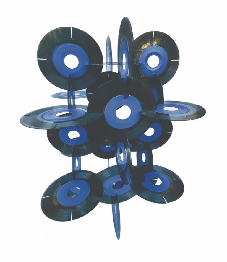 A sculpture made of numerous interlocking 7-inch vinyl records with blue labels. 