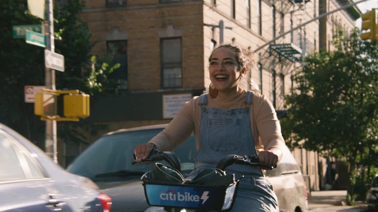 A woman on a bike is riding down the street while smiling