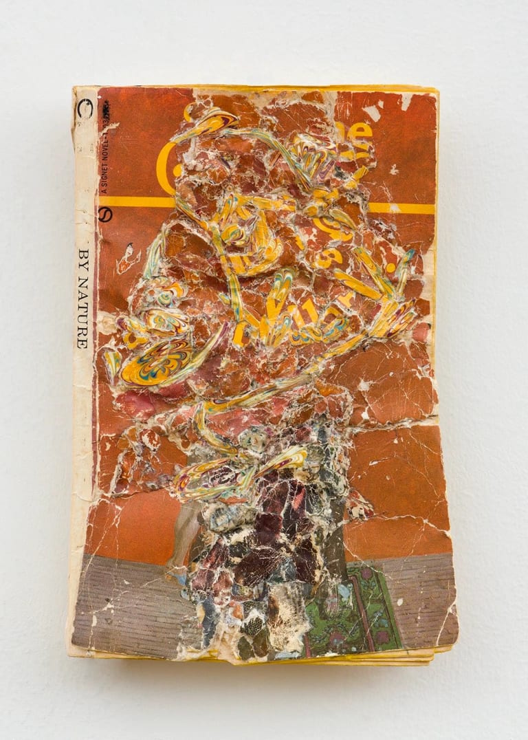A book with an orange and yellow cover that has been cut up and collaged into an abstract form.