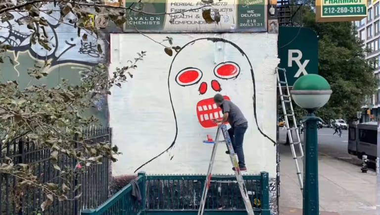 a man painting a mural outside of a train station