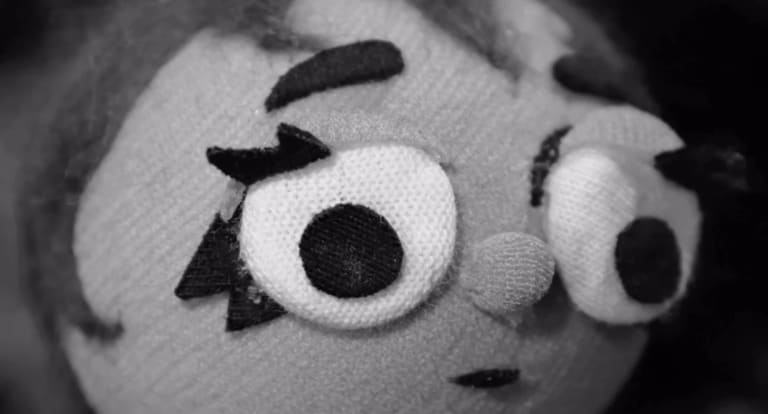 a black and white close-up film still of a stop motion face looking distressed