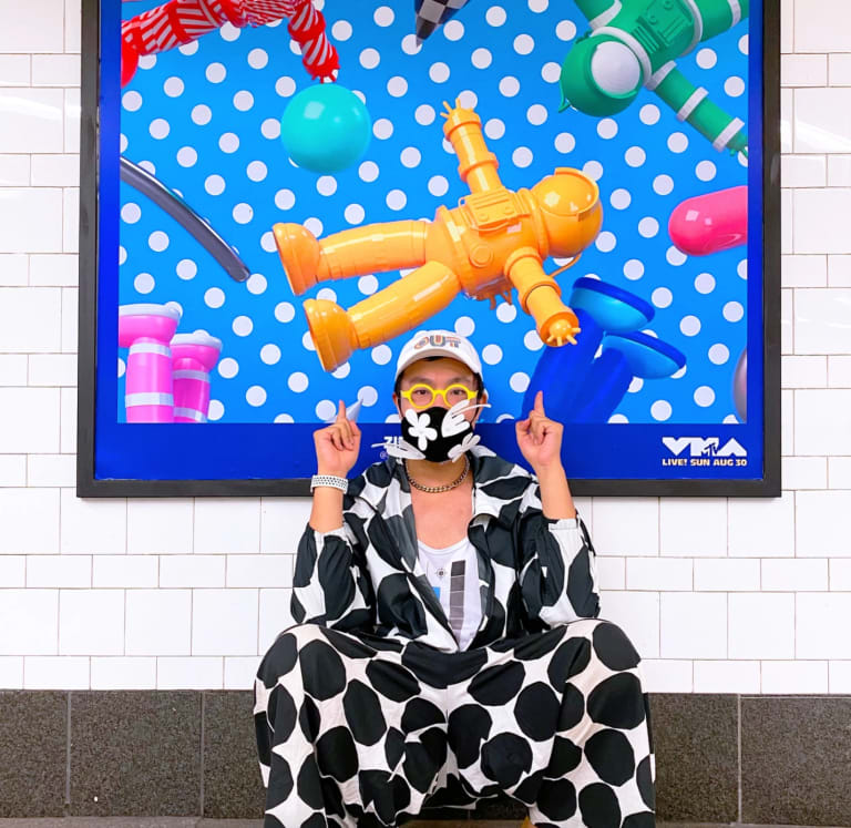 a man sitting in a subway pointing up at a poster 