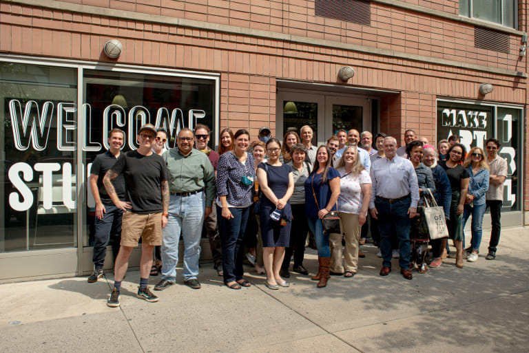 A group of directors of SVA's administrative offices pose in front of the SVA Student Center.