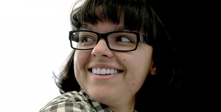 A younger woman with glasses looking behind her and smilling