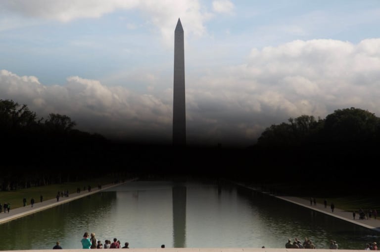 The Washington monument in viewed across the reflecting pool with a miasmic cloud partially obscuring the view of its base.