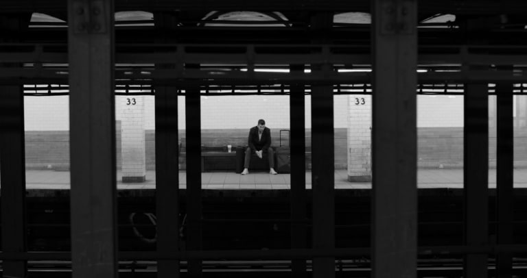 Man sitting waiting for a train in a subway