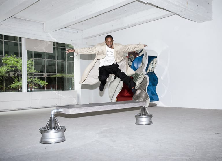 A young man jumping over an artsy bench.