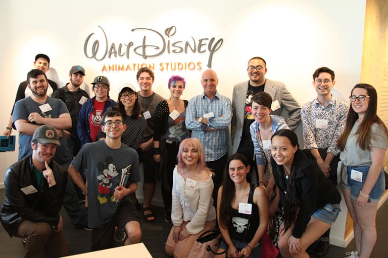 A group of people posed in front of a Walt Disney Animation Studios sign.