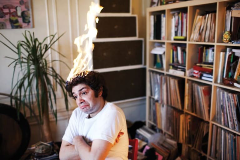 A man sitting with his hair on fire but he doesn't seem to care.