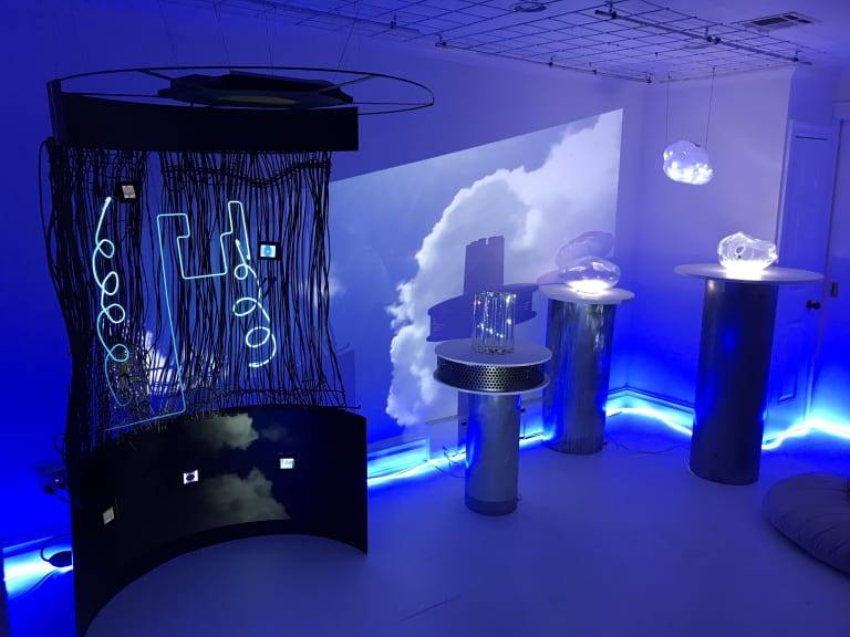 An art installation with neon lights, glass sculptures and clouds.