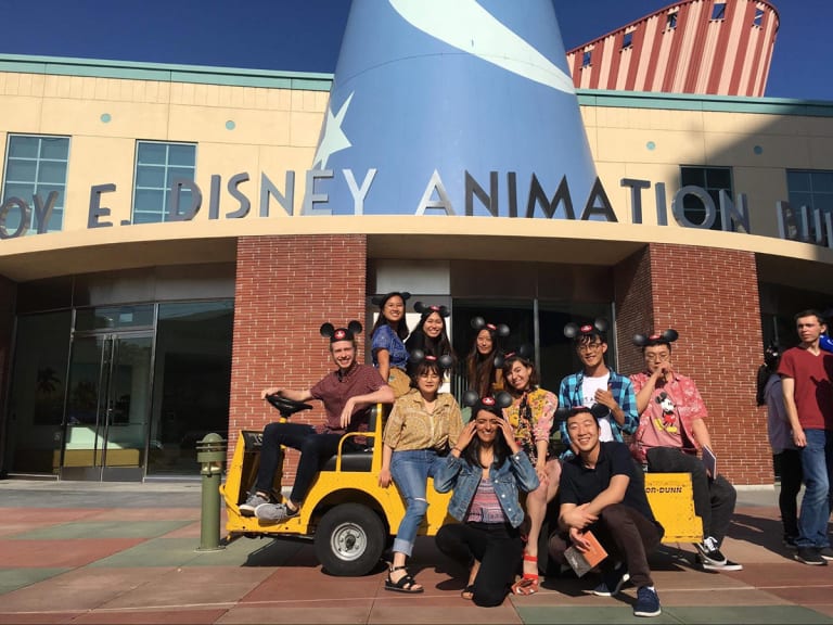 people posing for group photo outside Disney Animation Studio wearing Micky Mouse hats
