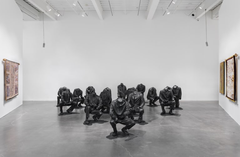 An art museum is showcasing statues of several people squatting.