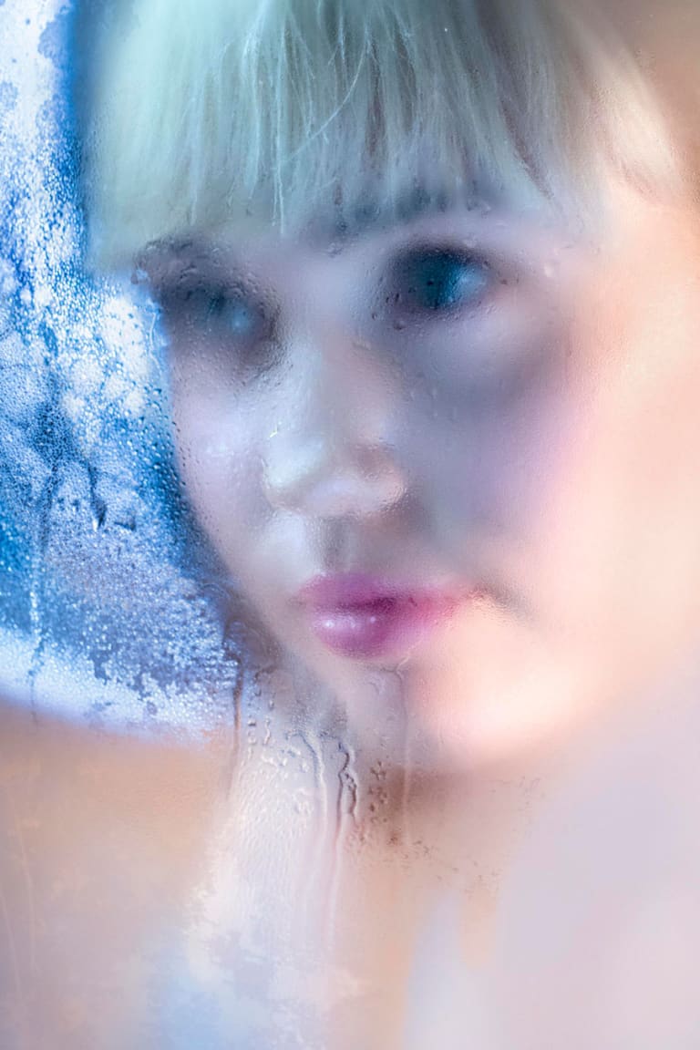 woman looking through water frosted glass