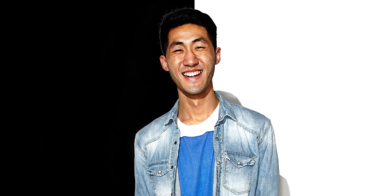A young man wearing a denim jacket and smiling.