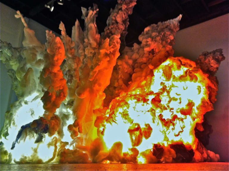 large sculpture made of natural silk and plastic lit with red, yellow and blue lights to portray a massive explosion.
