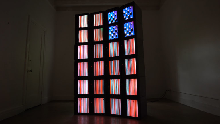Video sculpture of 24 televisions stacked on top of each other resembling the American flag
