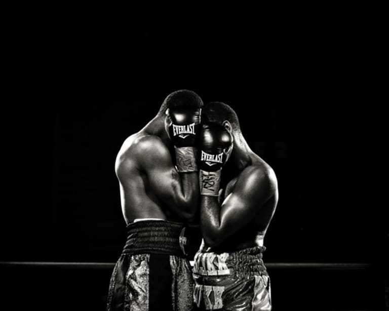 Two men wearing boxing attire standing closely in front of each other.