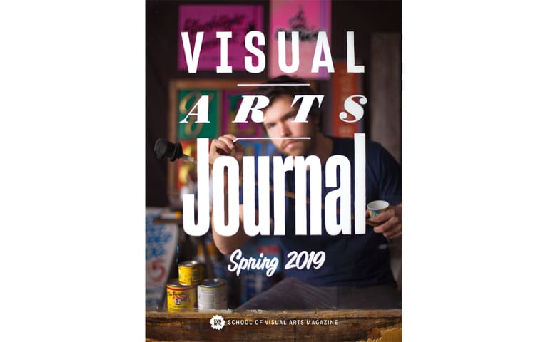 <p "="">A man puts the finishing touches on a glass pane painted with the words "Visual Arts Journal Spring 2019." <strong><br></strong>
