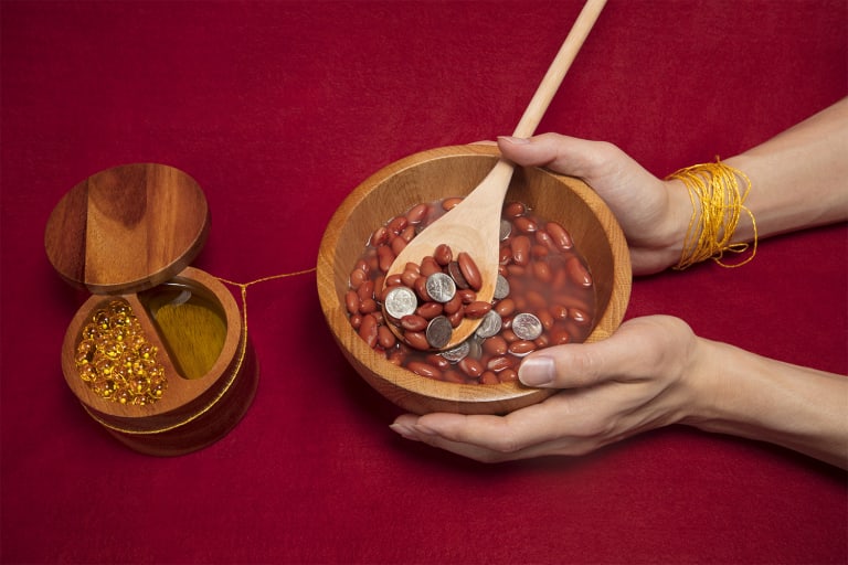 <p "="">A color photograph of two wooden containers, one holding pills and oil and the other holding red beans and dimes.

