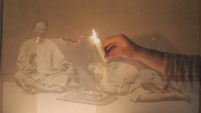 A hand holding a candle burns a piece of paper. Superimposed across the image is a 19th century B&W photograph of Chinese men smoking opium.