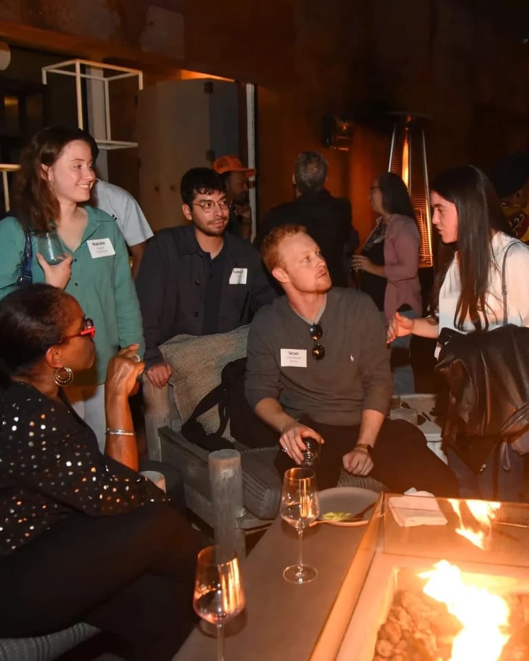 SVA Alumni gather around a fire pit on a rooftop during a gathering.