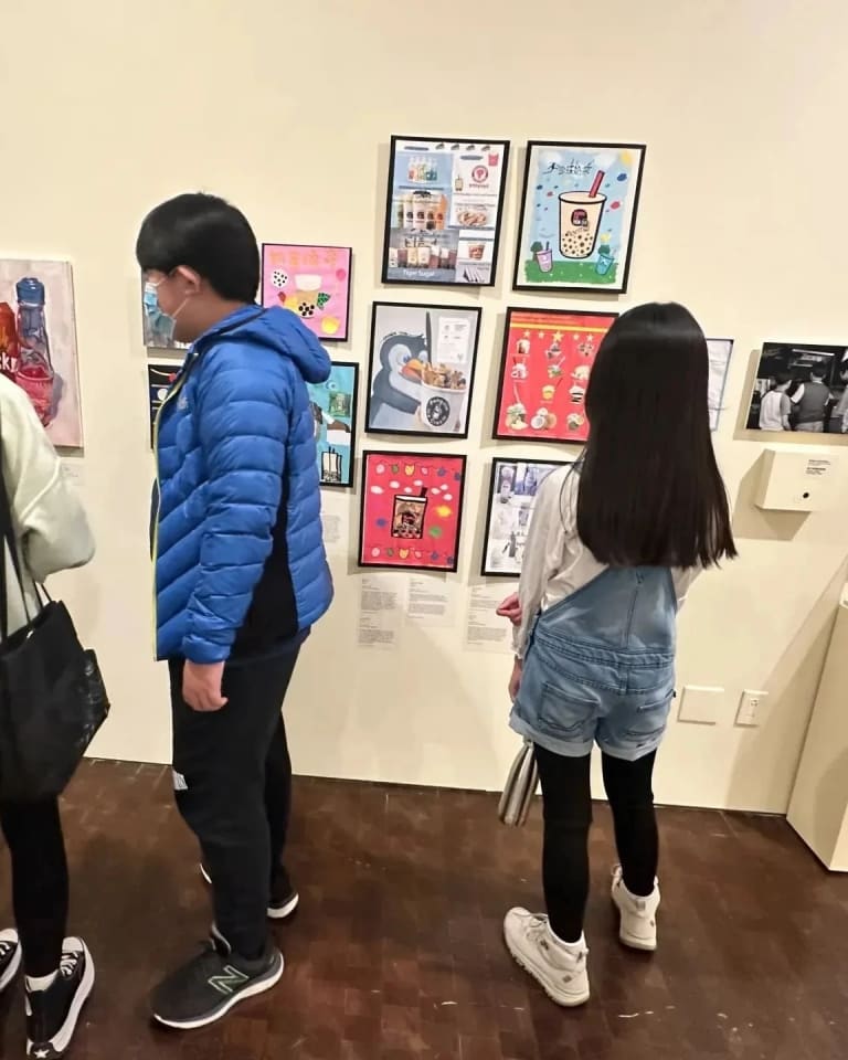 Picture of a few children looking at framed artwork at a museum exhibition.