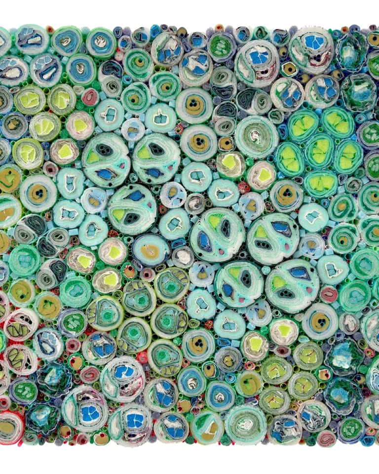 Image showing a rectangular canvas made of rolled plastic materials and cut straws, together forming a tapestry of circles of varying sizes.