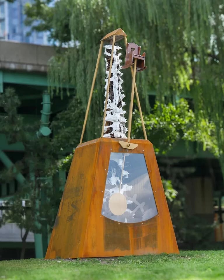 an orange sculpture in a green park area