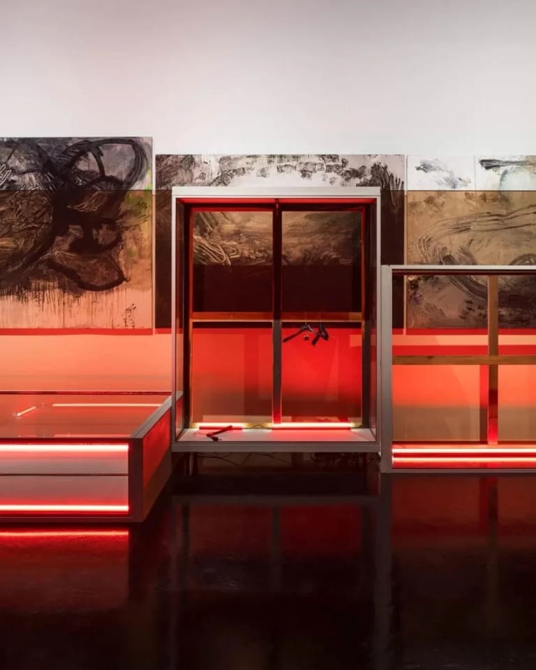 A plexiglass vitrine suspended aloft from the gallery’s four corners anchors the exhibition. Illuminated from within, the installation evokes a discarded trophy case whose prizes spill out into the space.