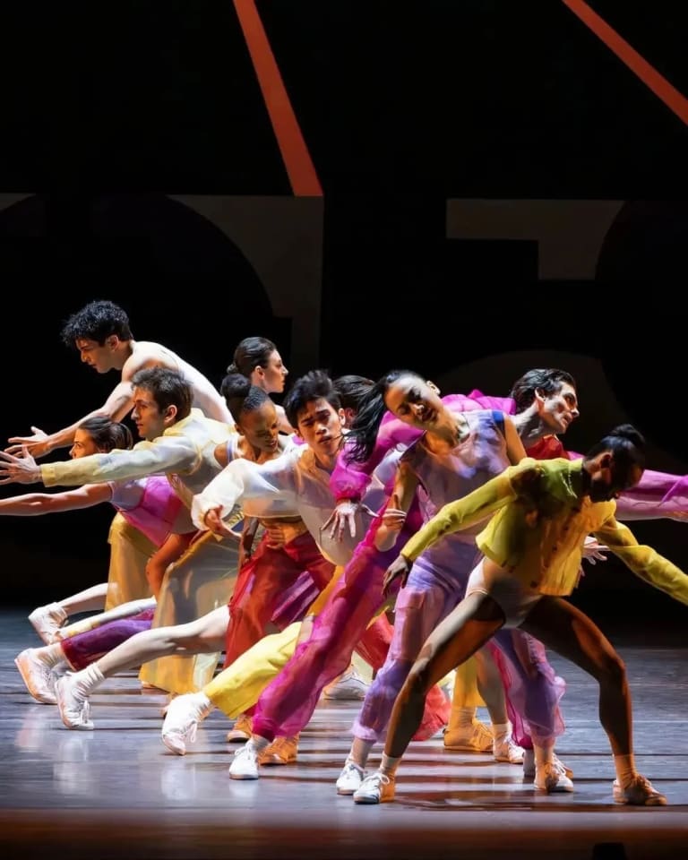 A vibrant group of dancers performing on stage, adorned in colorful outfits, showcasing their dynamic movements.