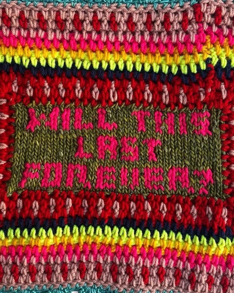 A rectangular artwork made of yarn with multiple concentric rectangular frames in many colors surrounding a central weaving containing the words “Will This Last Forever?”