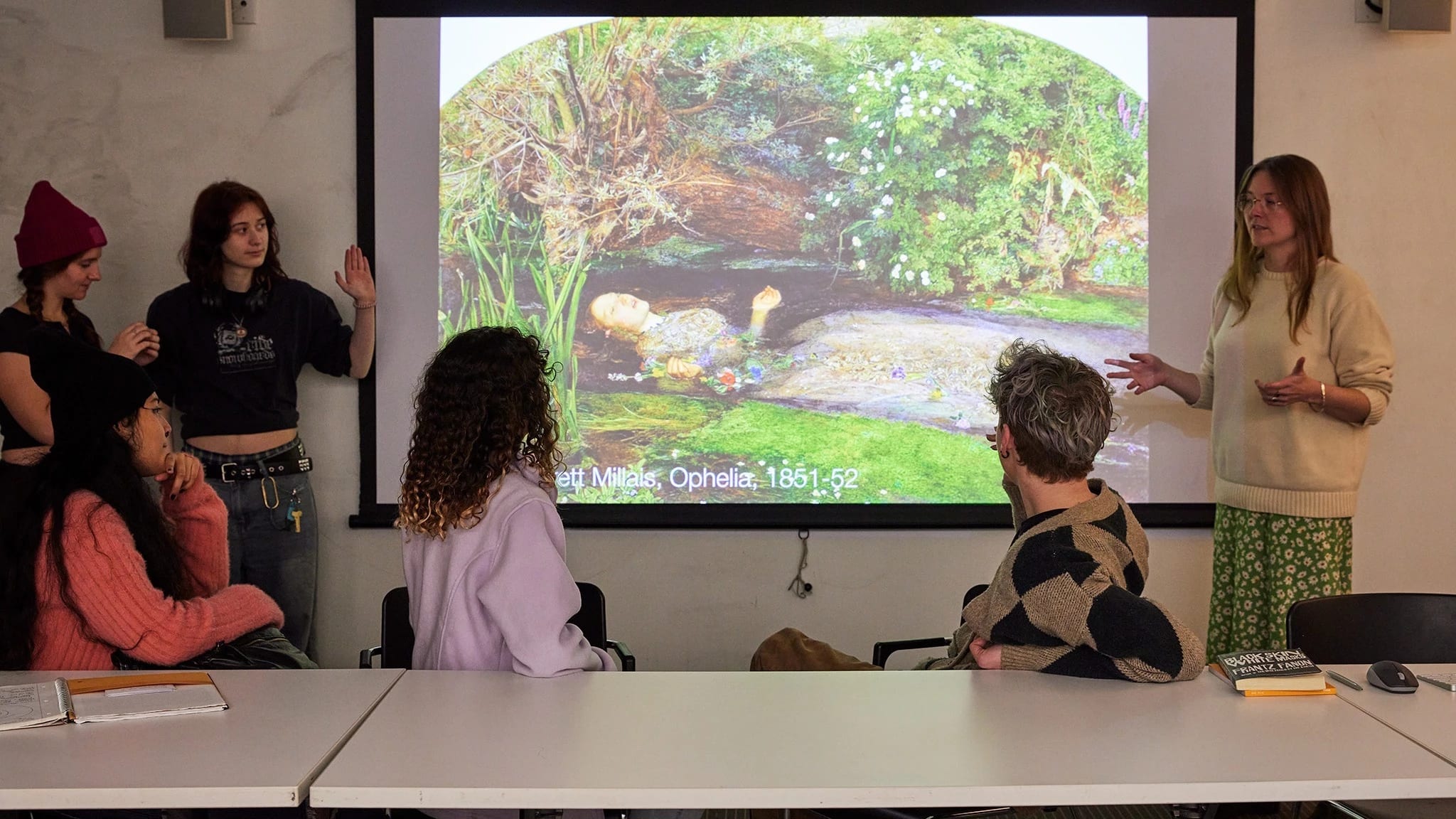 Image of students in a seminar style classroom discussing a work of art during class.