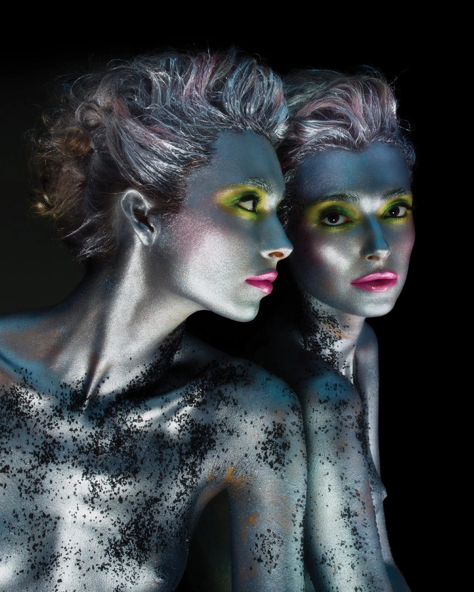 Nude woman from the chest up, painted with silver paint, looking into a mirror, seeing her reflection.