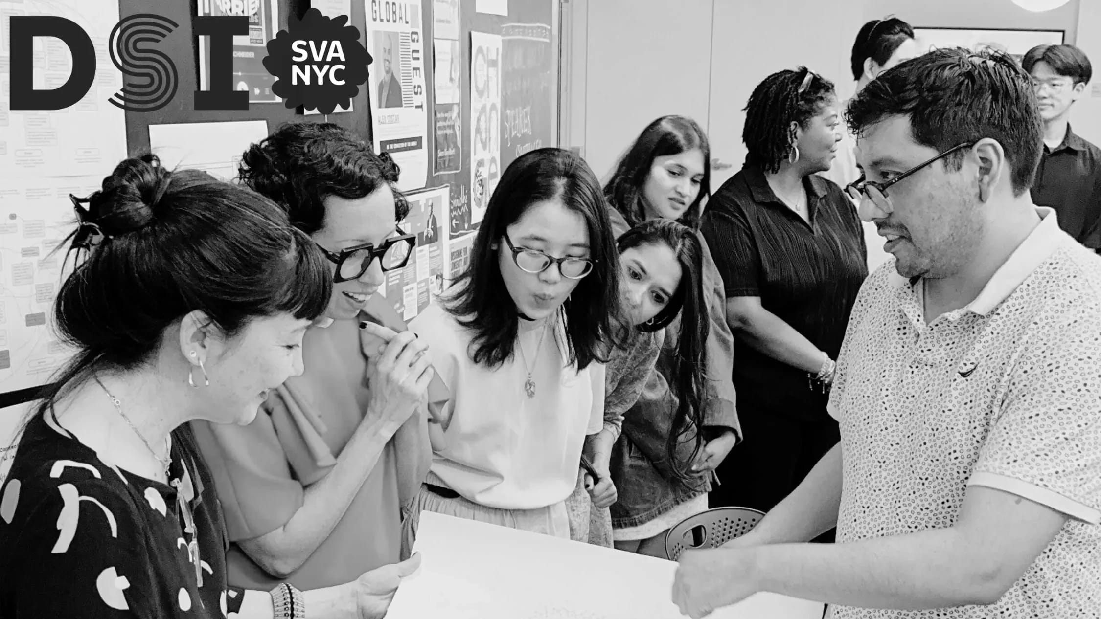 Black and white photo of students with instructors looking at a poster in the middle