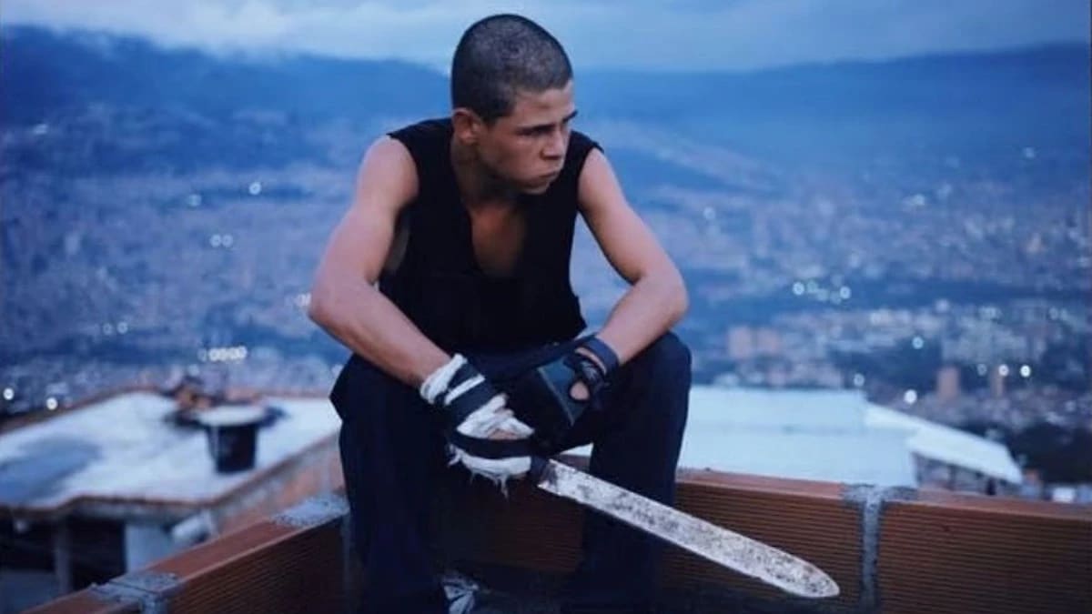 Boy sitting on a roof holding a machete