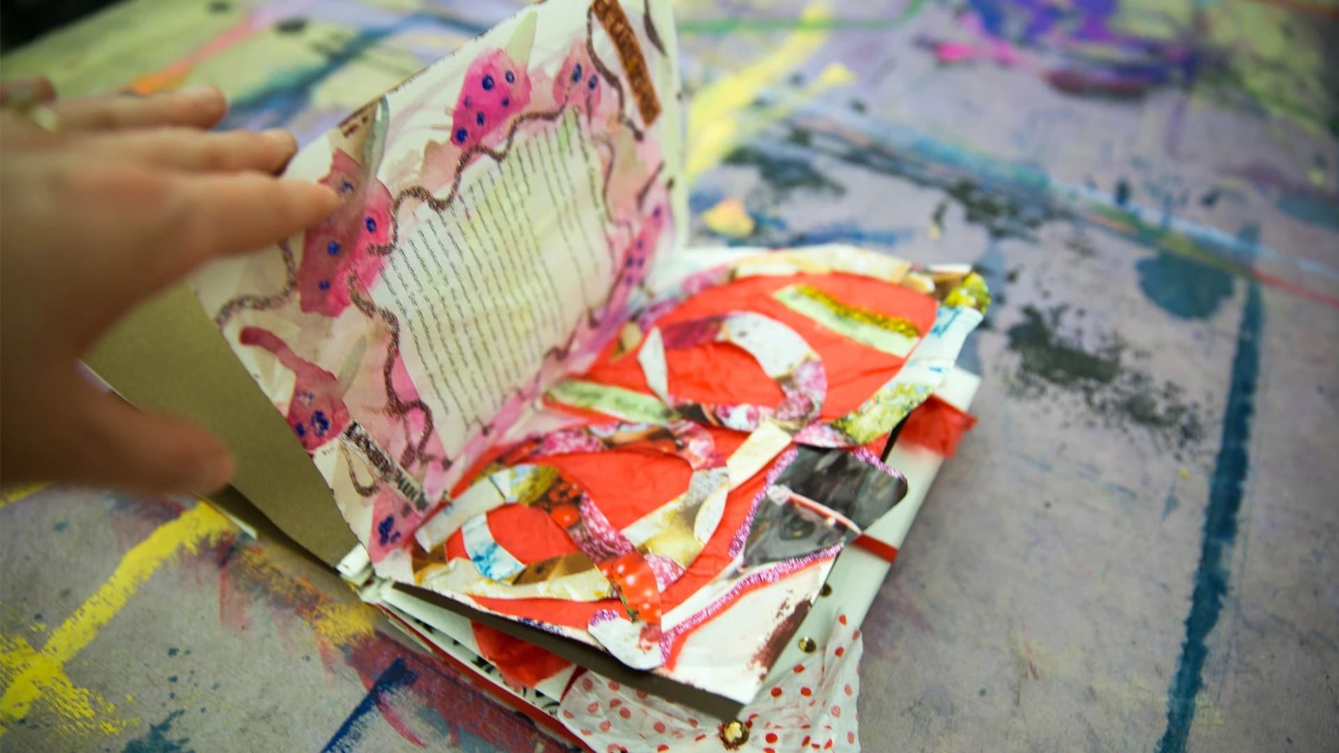 hand flipping through a collaged book